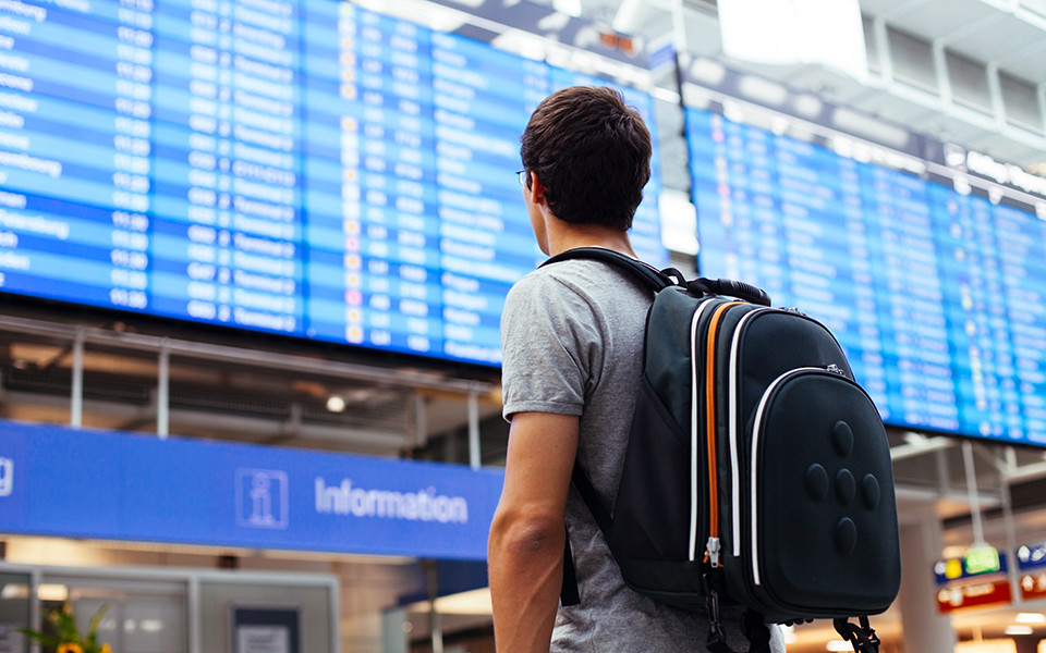 Mann vor Anzeigetafel am Flughafen