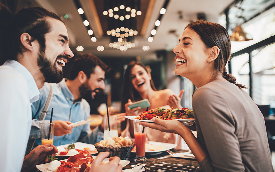 Freunde im Lachen und genießen gutes Essen in einem der Restaurants auf einem Kreuzfahrtschiff